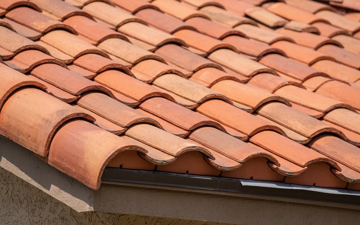 Close view of red clay barrel tile courses interlocking from the eave up, the eave closure neat.