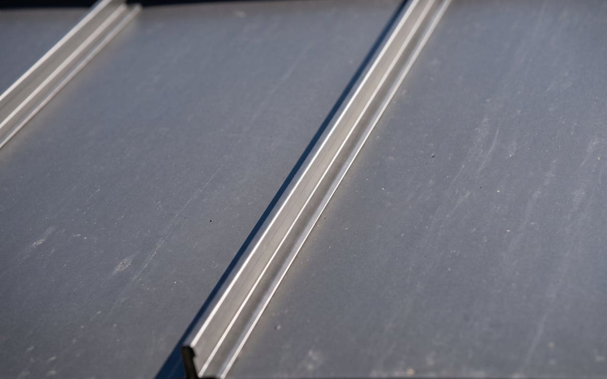 Close view of a charcoal standing seam panel and its seam in morning light.