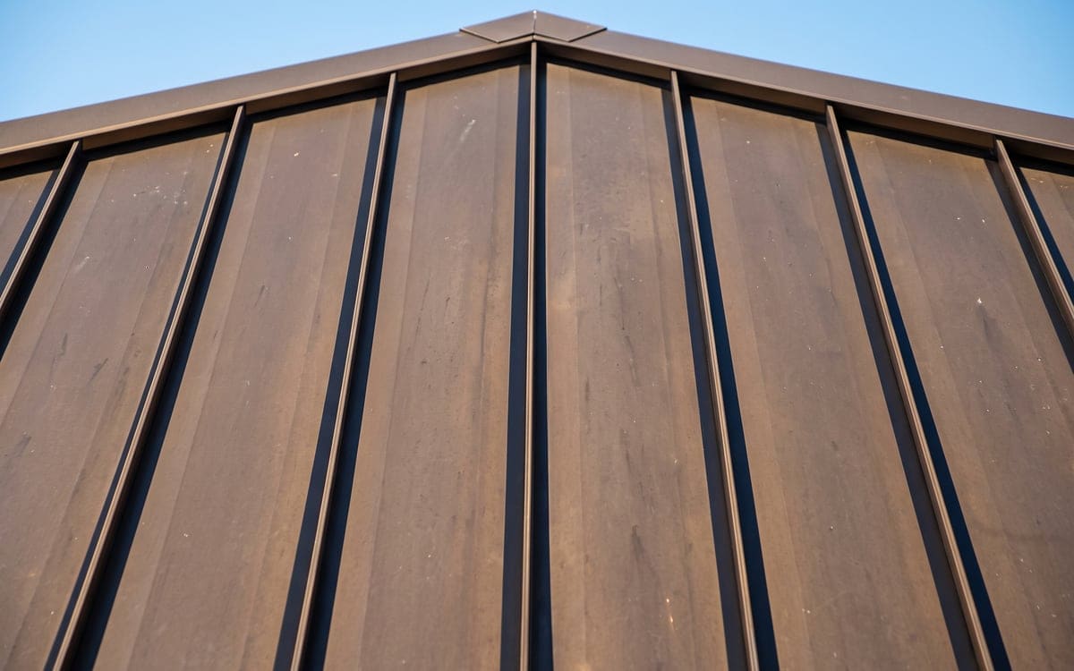 Close view of standing seams running up a bronze metal roof toward the ridge.
