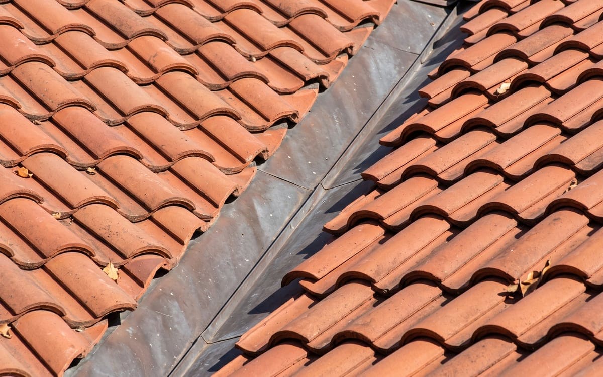 Close view of a metal valley in a red tile roof, tiles cut neatly along both sides.